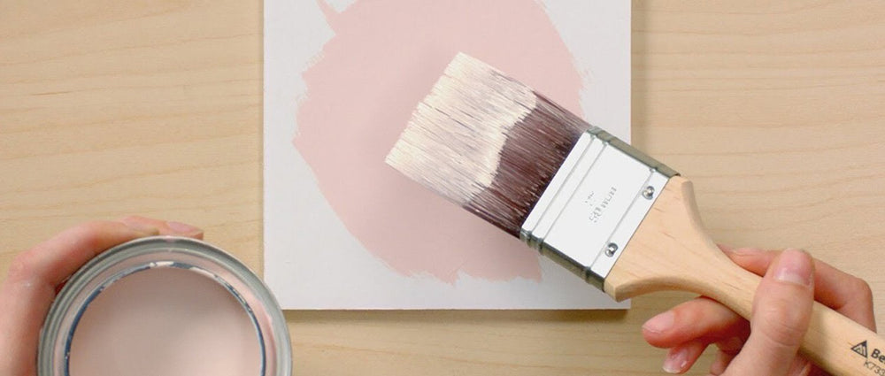 top down view of paint brush paint can and white block with pink circle painted on